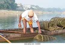 fisherman-in-wooden-boat-checking-his-fishing-pots-made-from-coir-cxdw91.webp