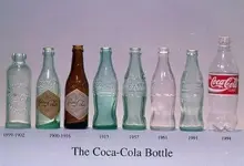 Coca Cola Lineup Of Bottles With Dates.webp