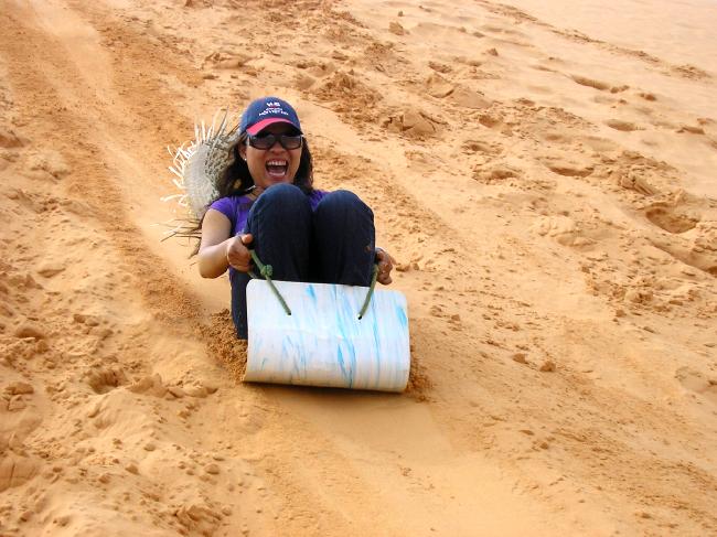 girl going down the sand dunes in mui ne