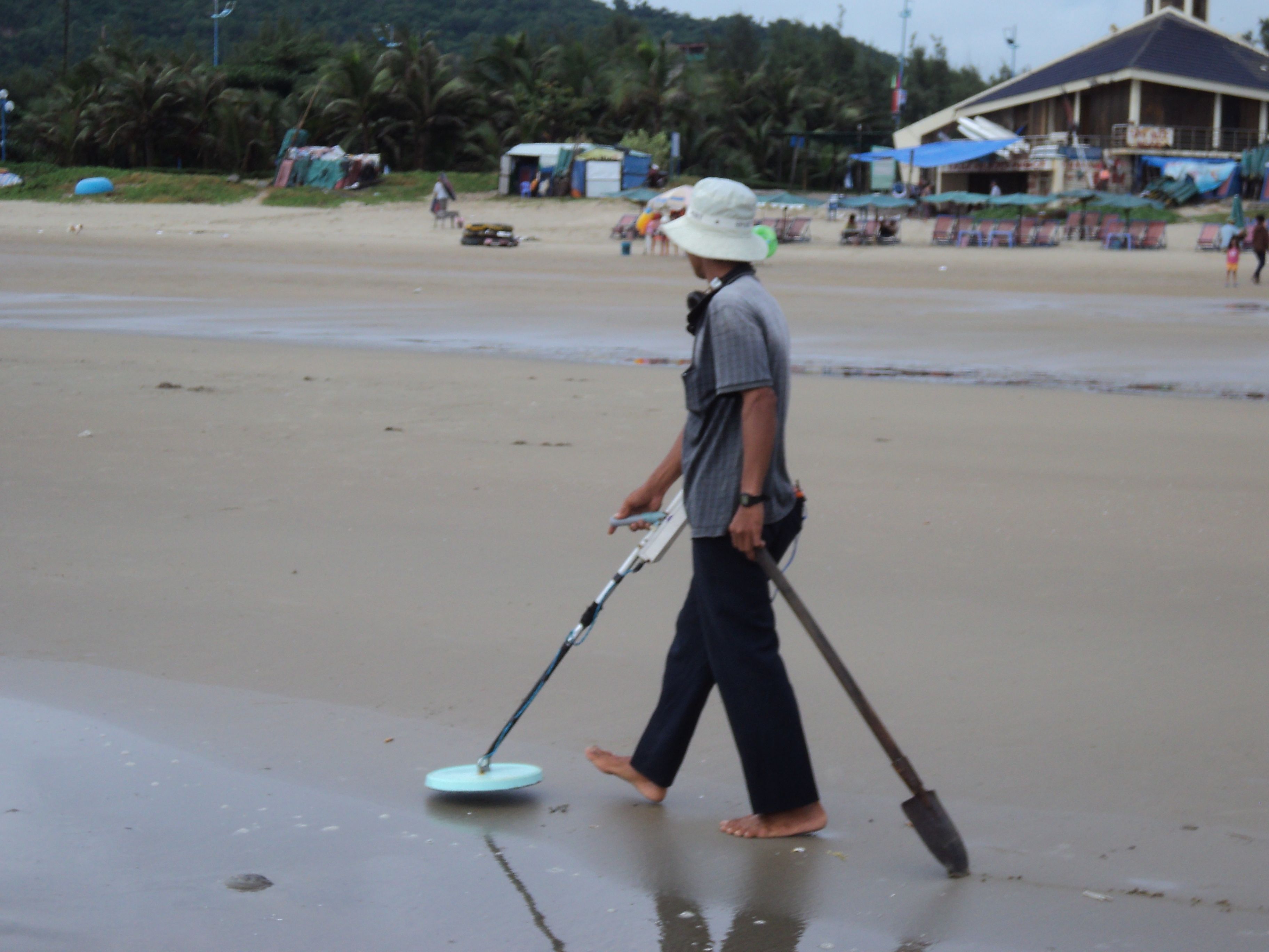 Vietnamese guy working the beach.  He drags the shovel behind him to mark where he's been.